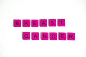 Pink Scrabble tiles forming the words 'Breast Cancer' on a white background, symbolizing awareness.